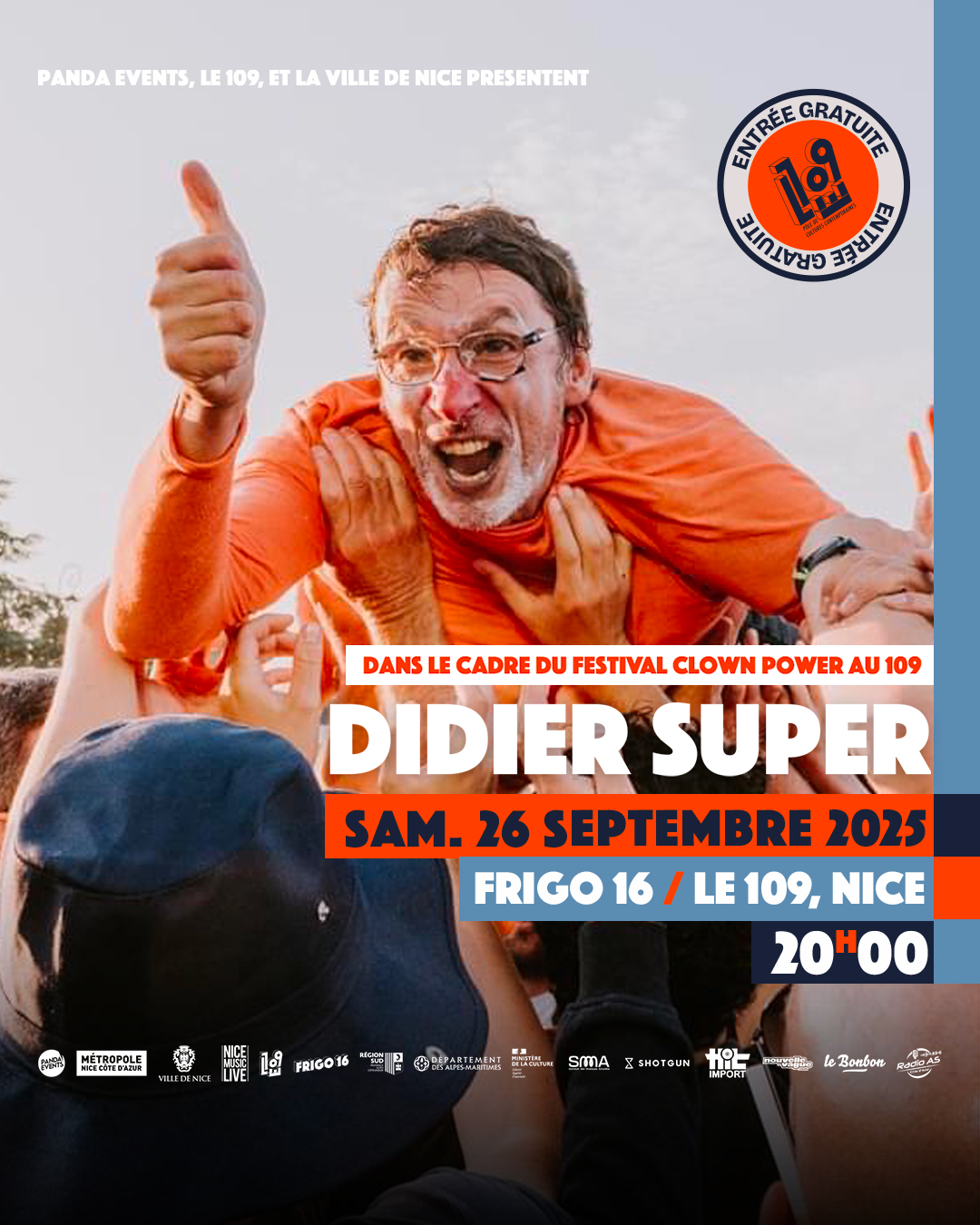 idier Super, porté par la foule, pouce levé, vêtu d'orange.
